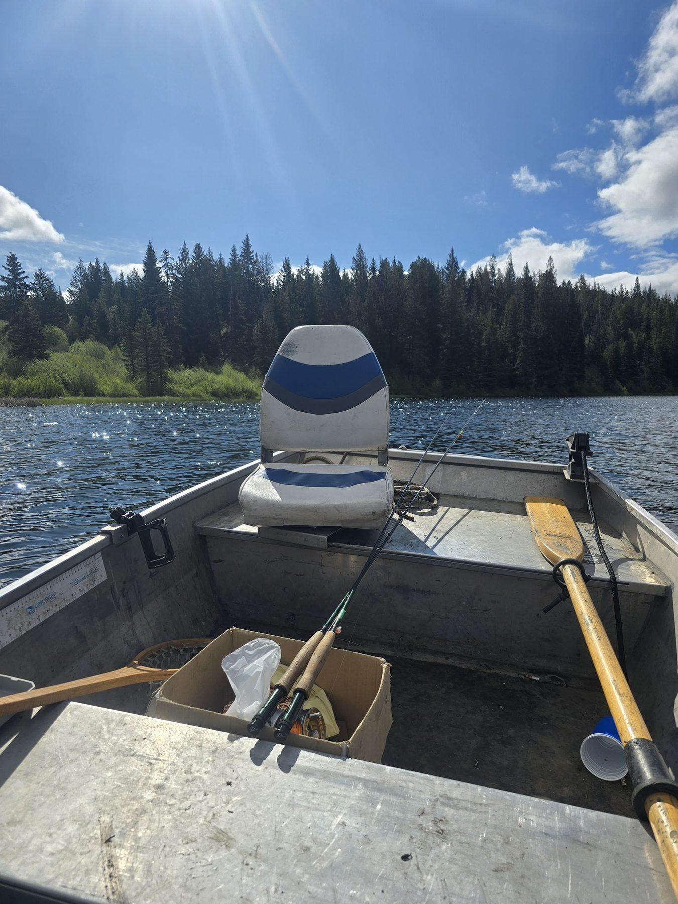 Boat setup facing a tree-lined stillwater lake